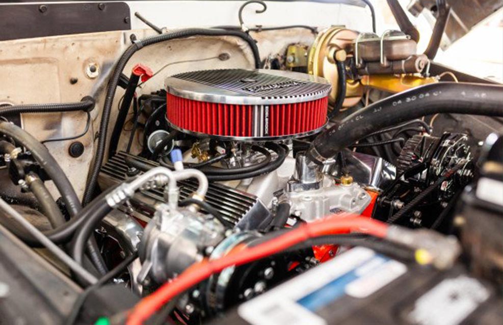 A close up of the engine and radiator of an old car.