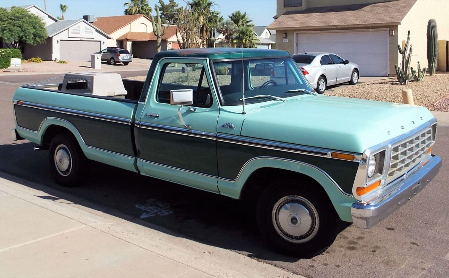 A blue truck parked in the driveway of a house.